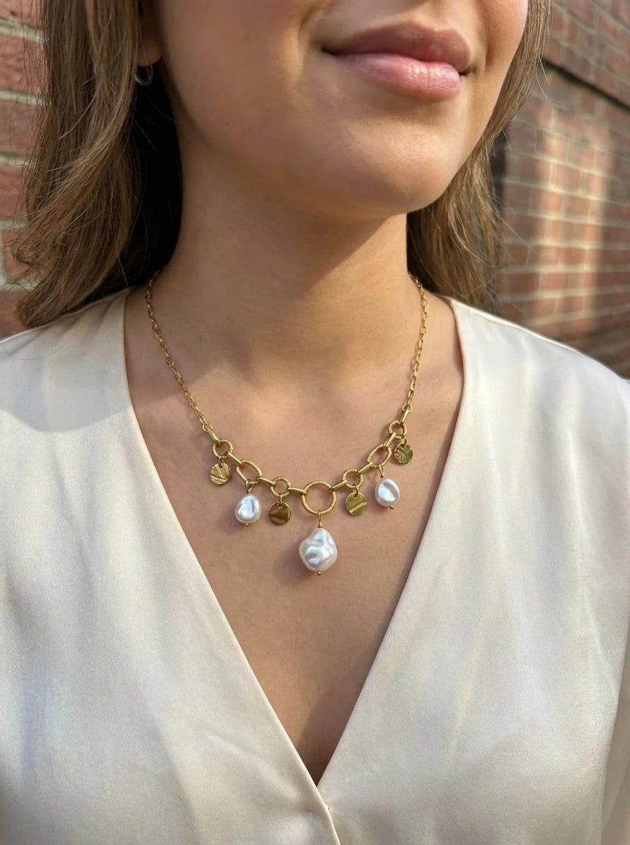 Collier Vaya doré à maillons avec médaillons martelés et perles blanches porté sur un haut blanc
