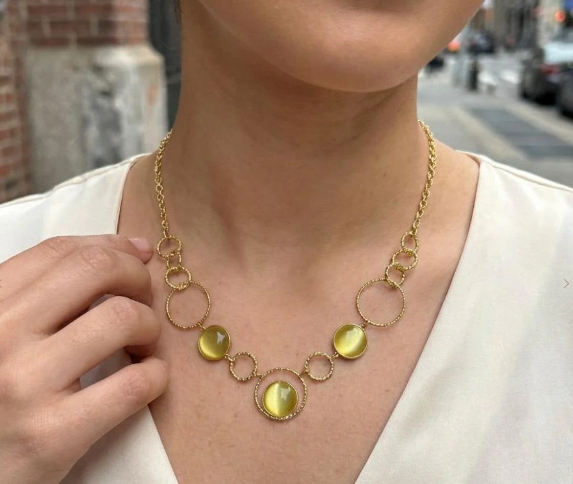 Collier Garance doré porté sur col en V blanc, 3 cabochons œil de chat vert et chaîne anneaux tressés acier inoxydable - FLIDEA