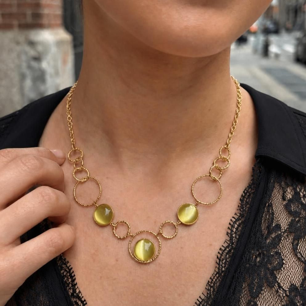 Collier Garance doré porté sur tenue en dentelle noire, cabochons œil de chat vert clair et anneaux tressés - FLIDEA