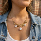 Collier Vaya doré à maillons avec médaillons martelés et perles blanches porté avec une veste en jean