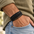 Bracelet homme Orion en cuir noir tressé, perles noires et détails en acier inoxydable 316L porté au poignet