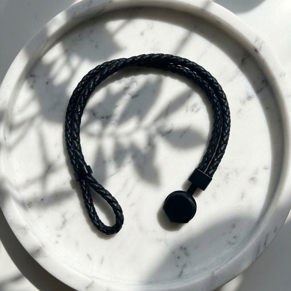 Bracelet Atlas homme en cuir noir avec fermoir argenté en acier inoxydable 316L posé sur un décor clair