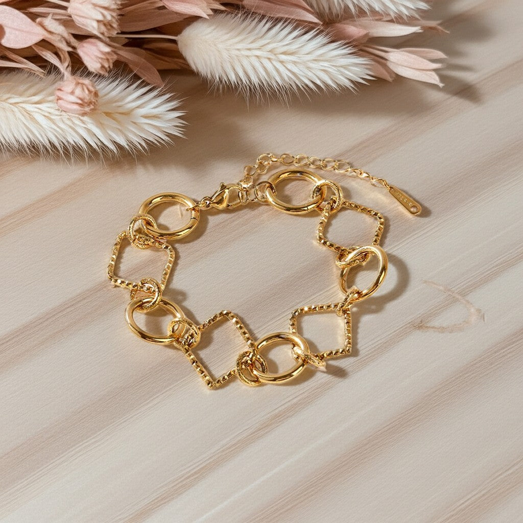 Bracelet Lizia doré à maillons ronds et carrés sur une surface en bois clair avec des fleurs séchées